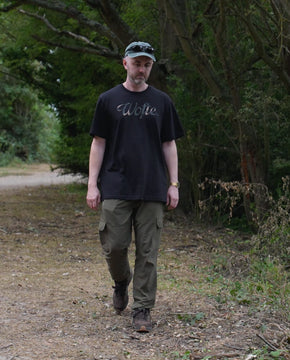 A man wearing a Wofte DPM Camo printed t-shirt walking next to a big carp fishing lake in Essex.