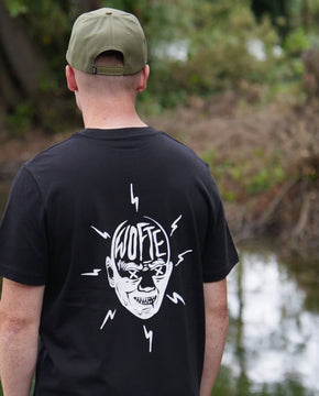 A man wearing a Wofte Carp Fever T-Shirt in black, walking around a big carp lake in Essex.