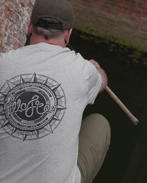 a man wearing a Wofte compass t-shirt in heather grey whilst carp fishing