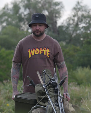 A video of a man pushing his carp porter barrow whilst carp fishing. He is wearing his Wofte Syndicate T-Shirt in a light brown colour.